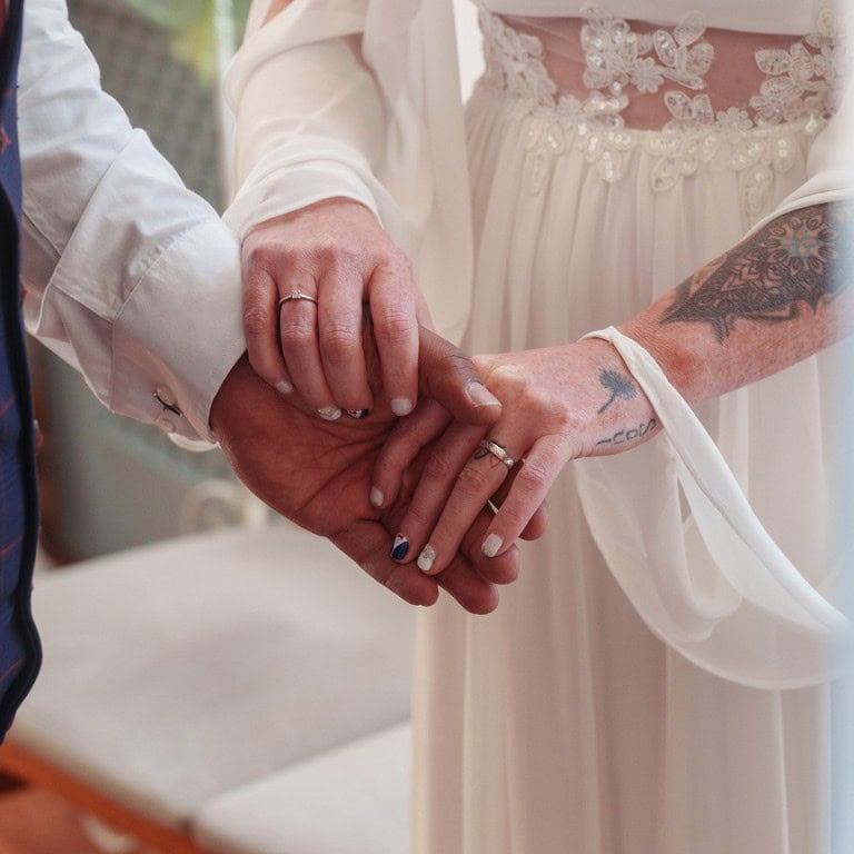 Engaged couple's hands with wedding rings, symbolising love and commitment.