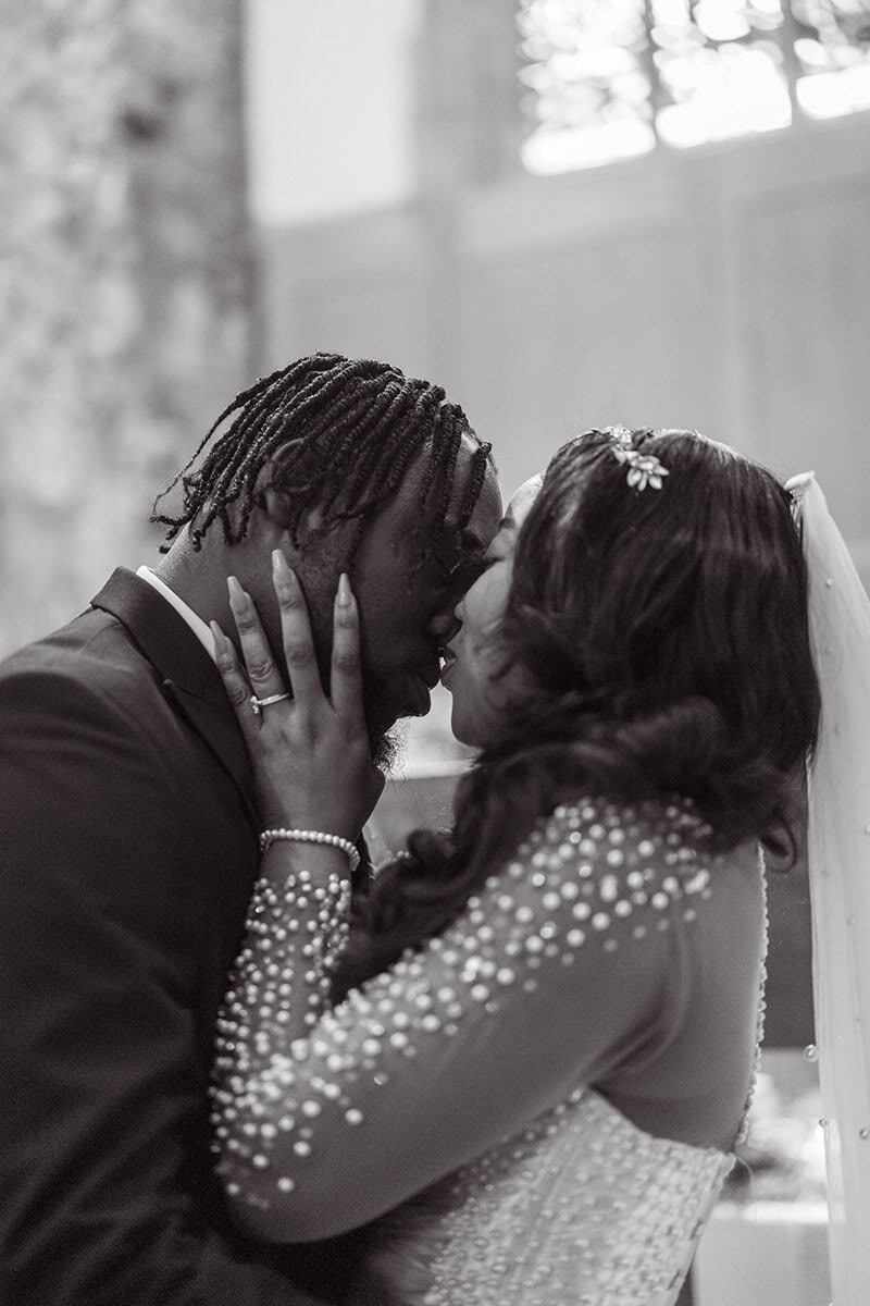 Romantic wedding couple sharing a kiss, black and white photography, intimate moment, bride and groom, love, wedding day, emotional connection, celebration.