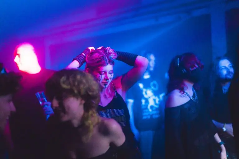 Vibrant nightclub scene with young people dancing under colorful lights, showing nightlife entertainment and socialising.