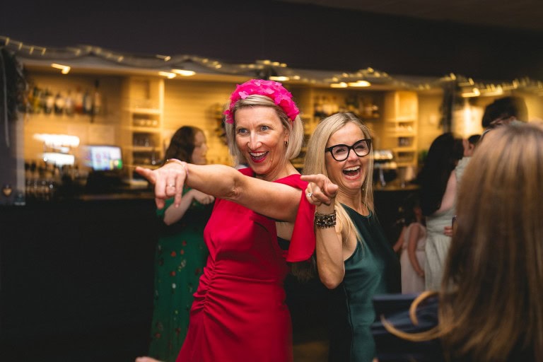 Vibrant women dancing and having fun at a lively party or celebration, dressed in colourful outfits.