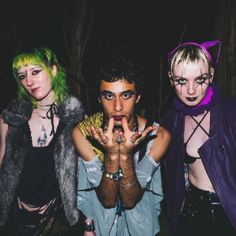 Vibrant alternative fashion group with bold makeup and unique styles outdoors at night.