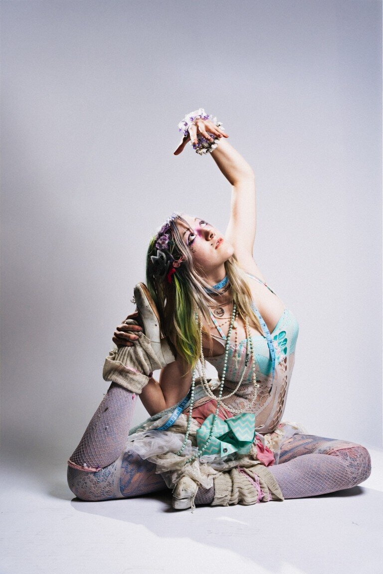 Colourful fashion model with eclectic accessories and vibrant hair in artistic photo.