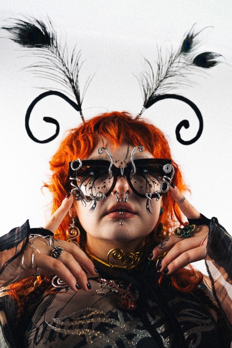 Peacock feather headpiece, avant-garde jewellery and sunglasses, bold fashion statement, creative costume, alternative style.