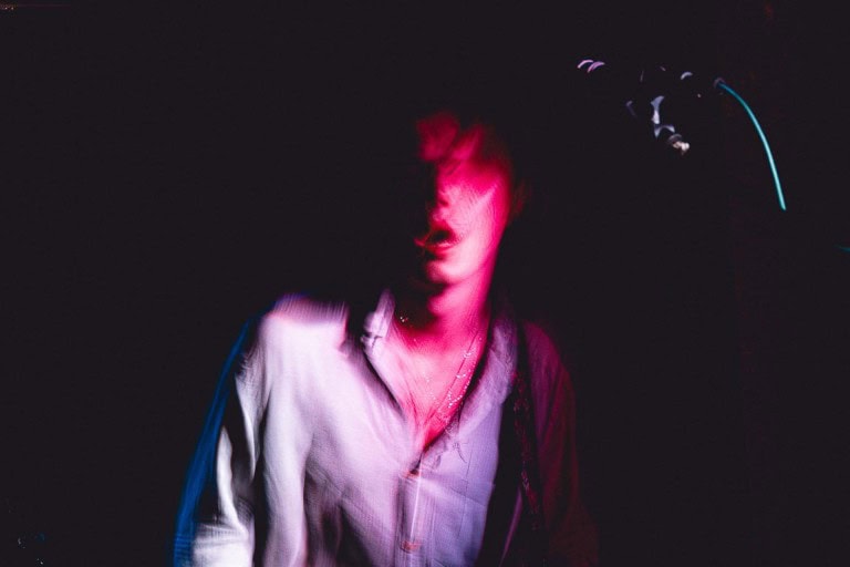 Neon-lit woman with pink lighting, nightclub or concert vibe, artistic nightlife photography, vibrant party scene, loose casual style, modern urban atmosphere.