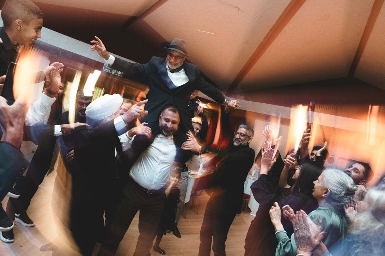 Celebration with a joyful group dancing and cheering at a festive event or party.