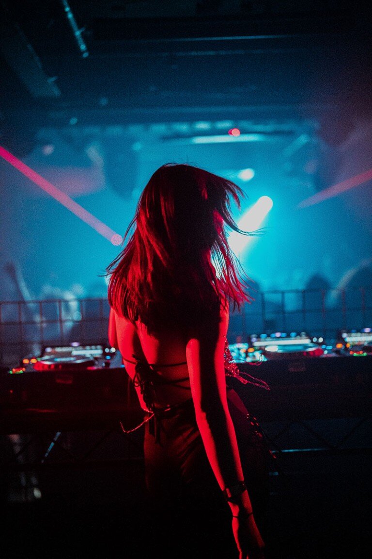 DJ woman dancing in nightclub with colourful laser lights, vibrant party atmosphere and energetic vibe.