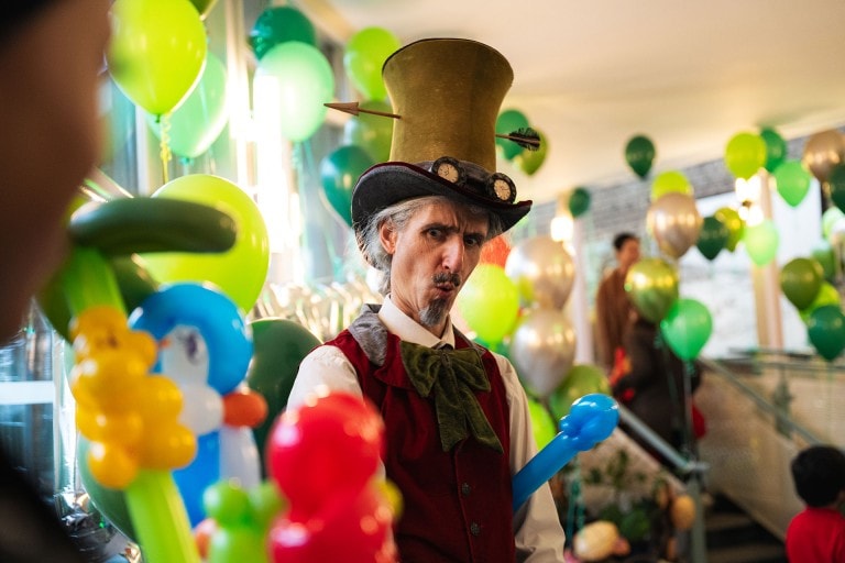 Colourful balloon decorations at a fun party, featuring a man in a whimsical costume with a hat and face paint.