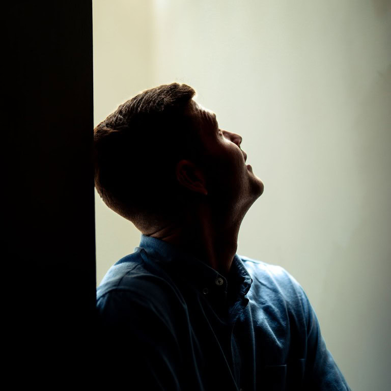 Silhouette of a man looking up by a window with natural light, contemplative mood.