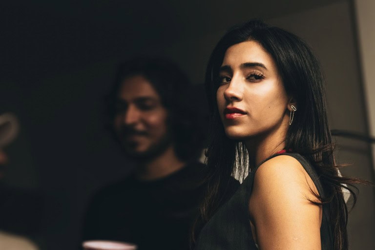 Elegant woman with dark hair, confident expression, nightlife style, stylish earrings, indoor setting.