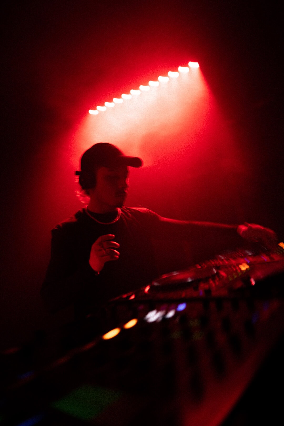 Red lighting DJ performing at night club, electronic music, vibrant club atmosphere, DJ mixing tracks.