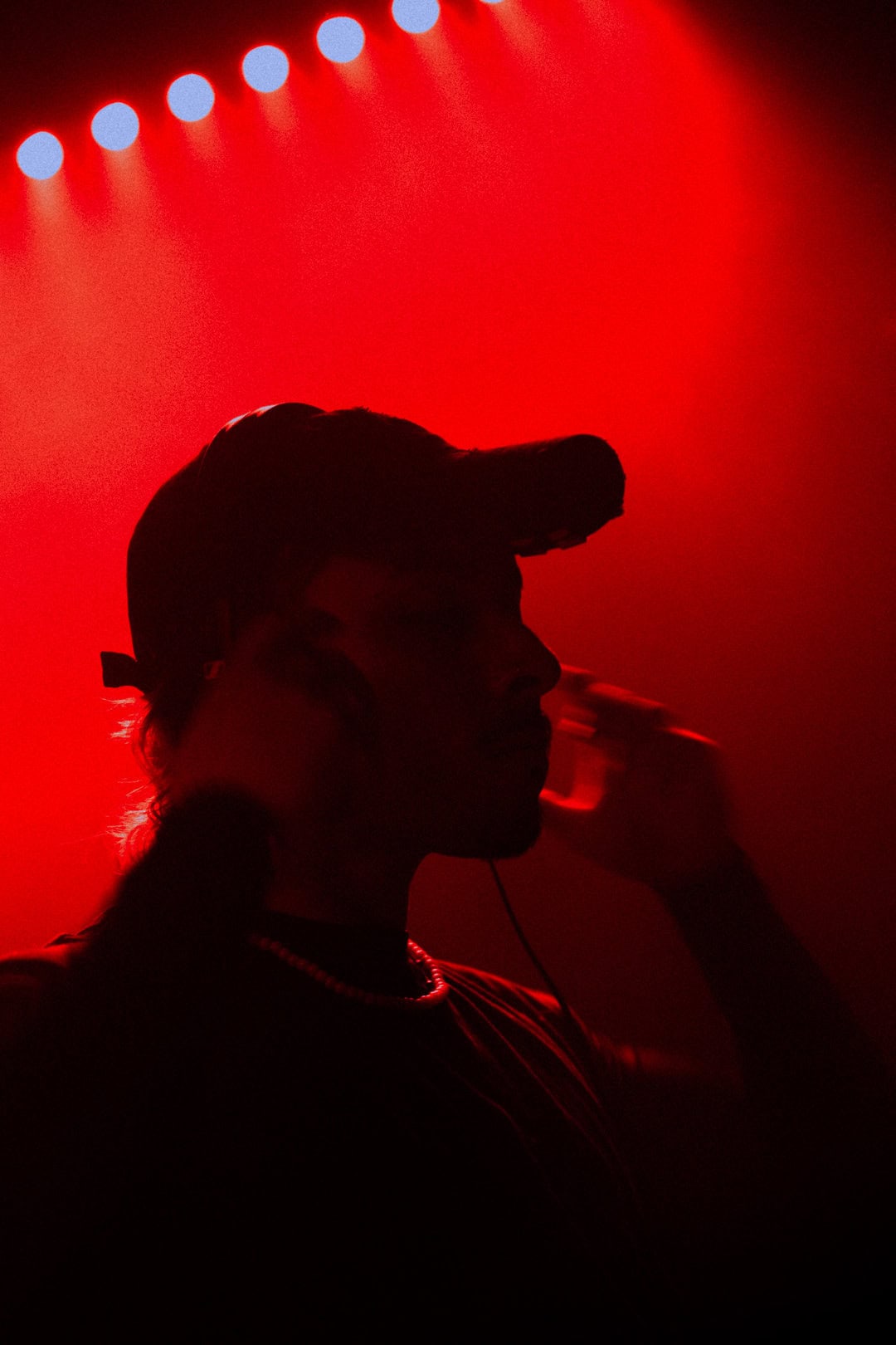 Silhouette of a DJ with headphones against vibrant red background, creating a dynamic and energetic atmosphere.