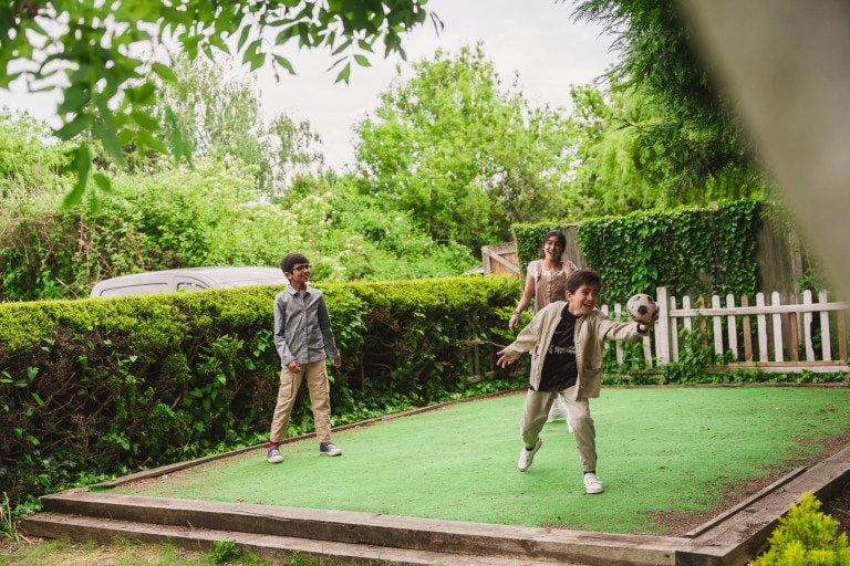 Kids playing mini golf outdoors in a lush green garden.