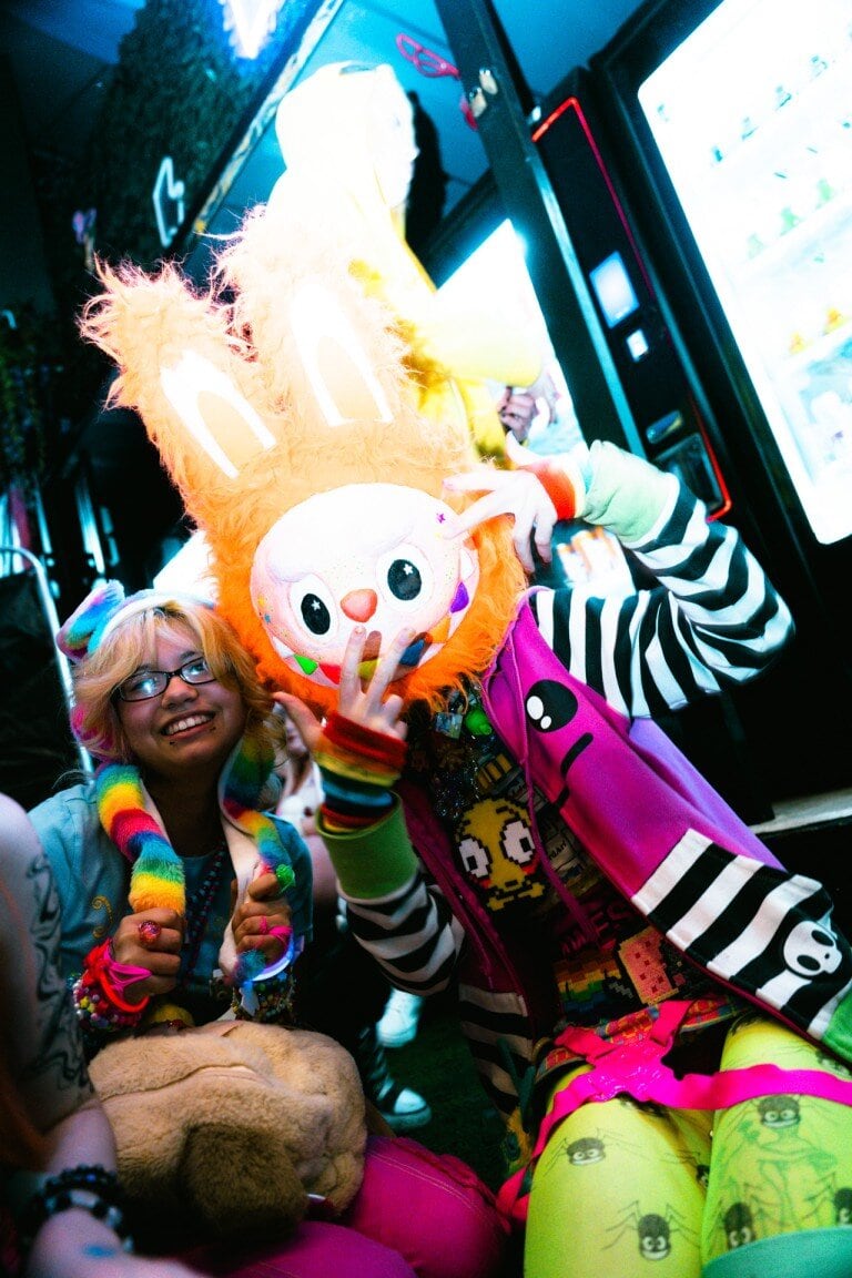 Brightly coloured partygoers at a neon-lit arcade, celebrating with vibrant costumes and fun accessories.