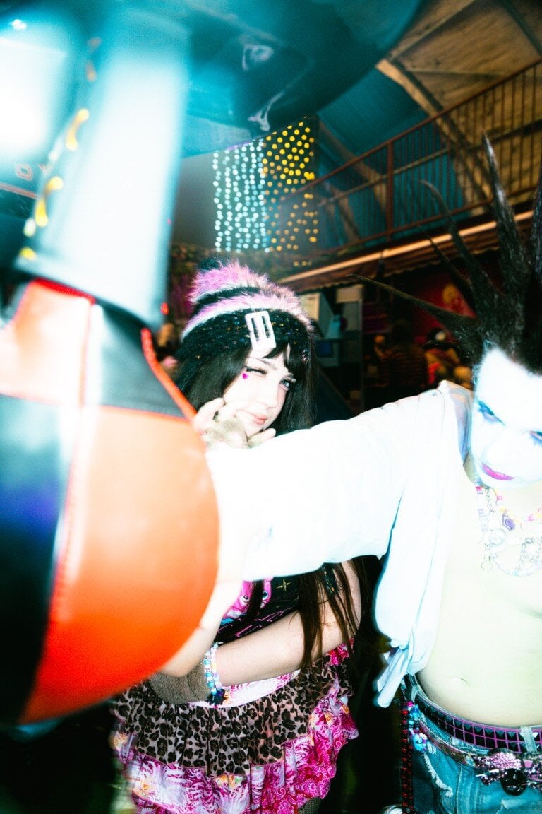 Bright young people enjoying a party indoors with colourful lighting and playful fashion.