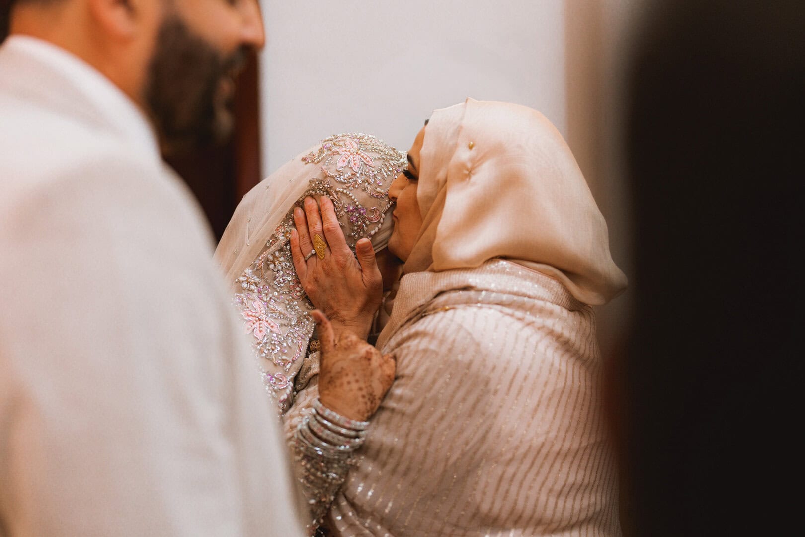 Bride sharing a tender moment with an elder, capturing emotional affection during a wedding celebration.