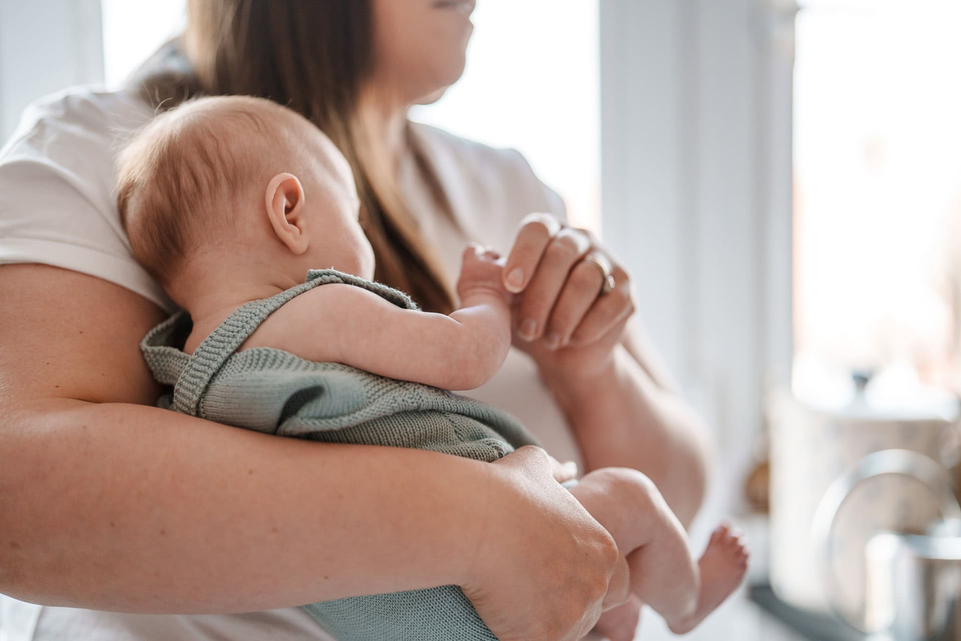 Gentle close-up of a person holding a sleeping baby in an indoor setting, highlighting nurturing and comforting moments.