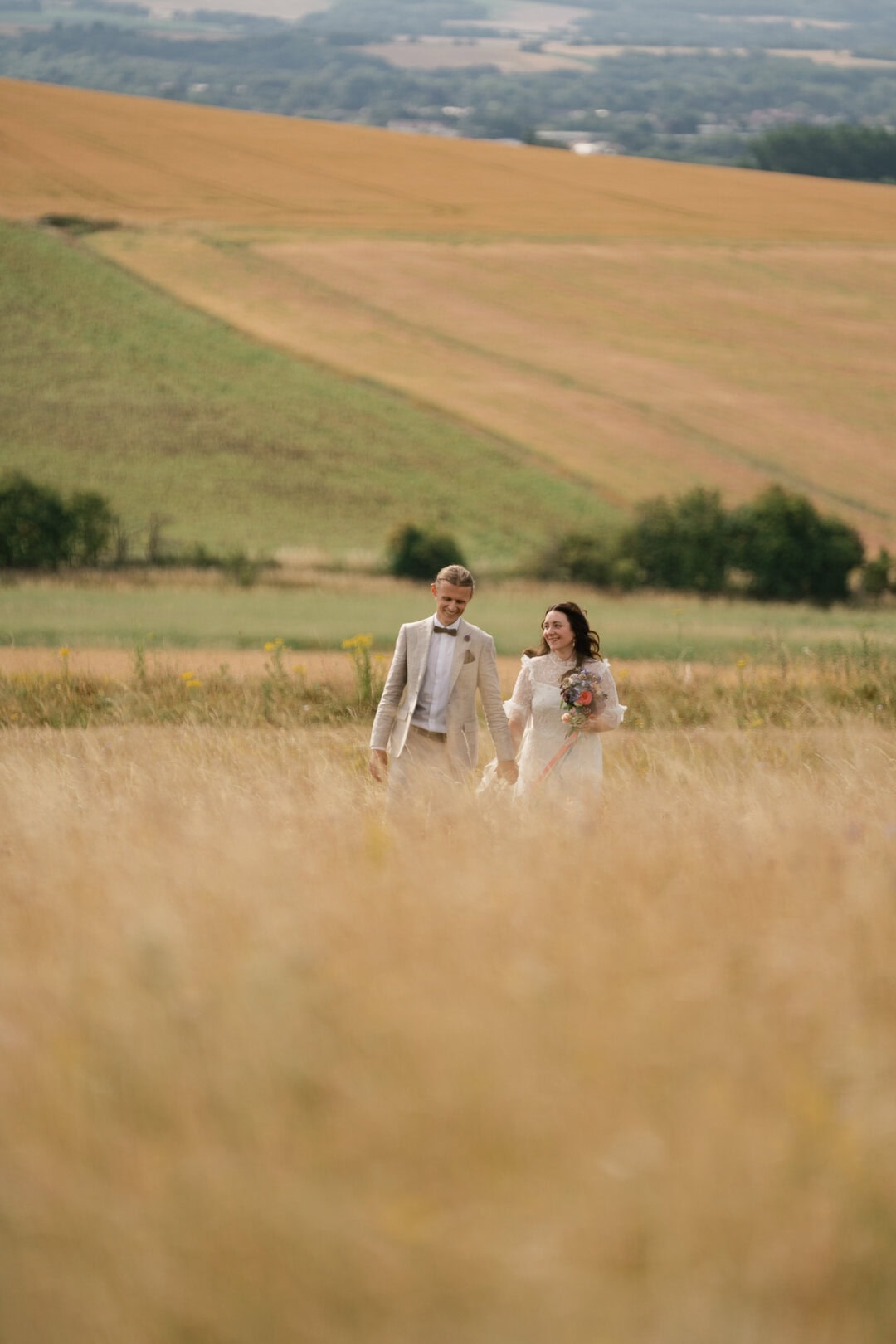 Golden couple walking in a wheat field during sunset, romantic wedding photography in countryside.