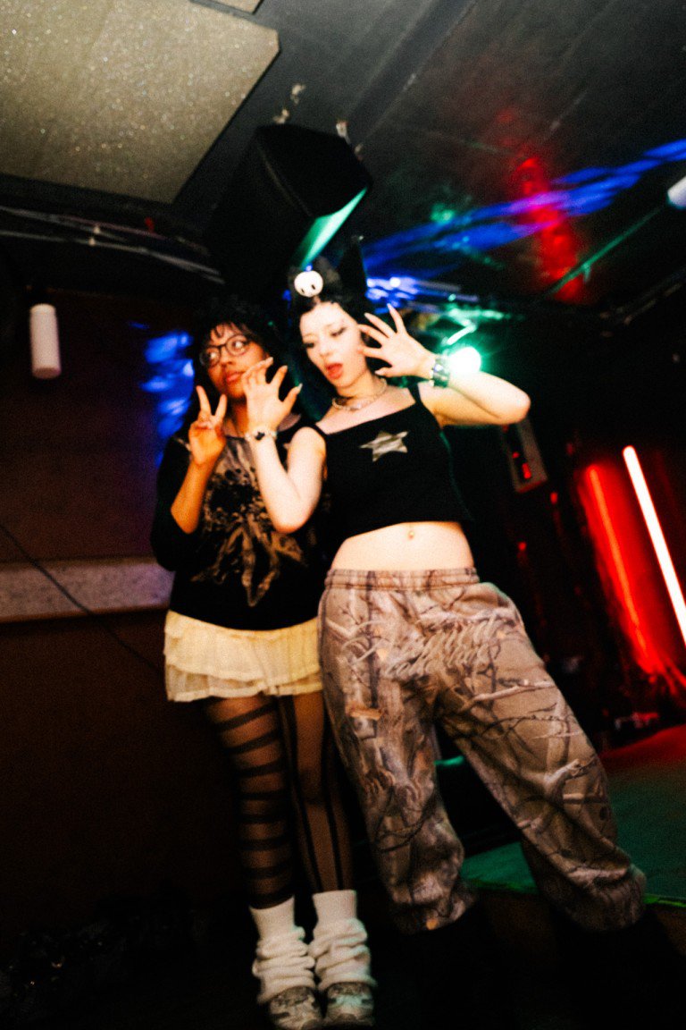 Vibrant nightlife photography capturing youthful women dancing at a club with colourful stage lighting.