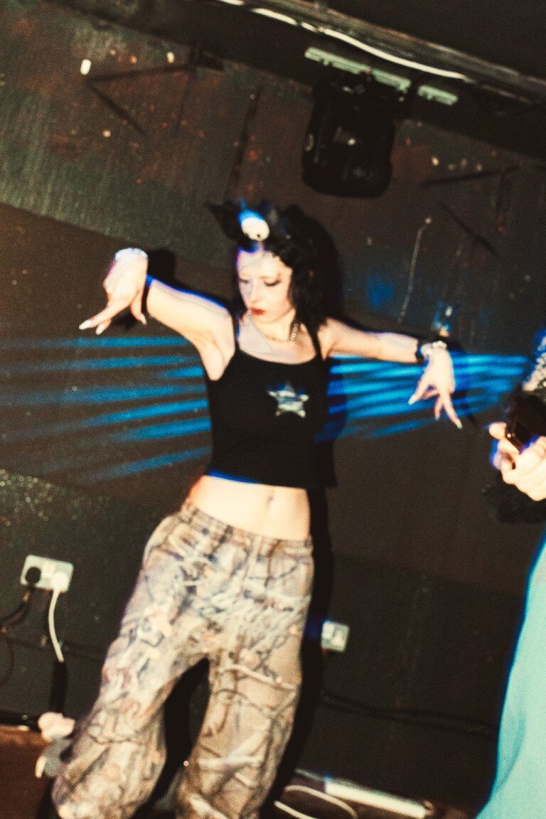Vibrant dance performance featuring a young woman in casual chic attire at a nightclub, capturing dance and nightlife photography.