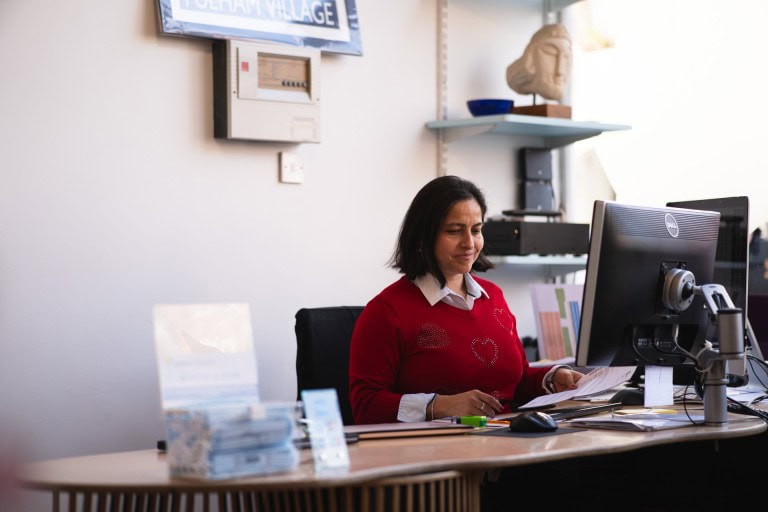 Studious woman works at her desk in a well-organized office space, surrounded by documents, a computer, and inspiring décor.