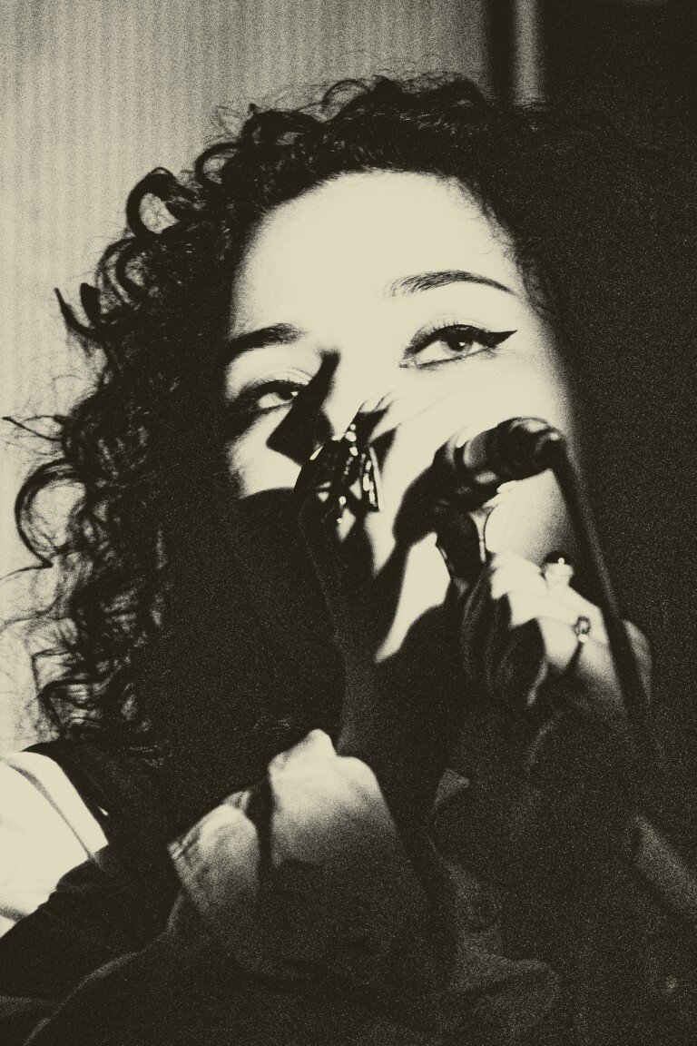 Vibrant black and white portrait of a female singer performing with a microphone at a live music event.