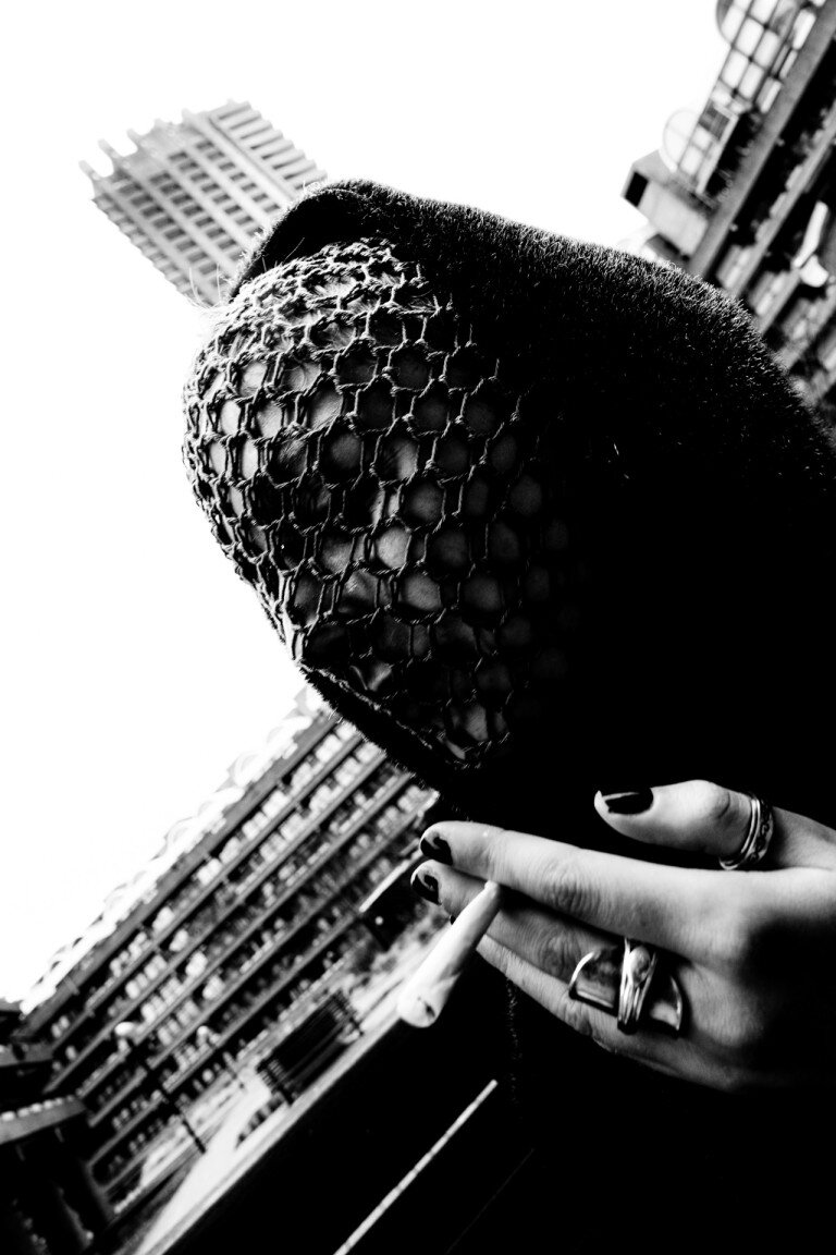 A person holding a textured clutch bag with a cityscape in the background, captured in black and white with an urban, modern aesthetic.