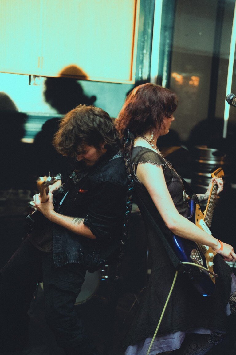 Dynamic live music performance capturing guitarists in an energetic concert setting, emphasising vibrant lighting and artistic expressions.