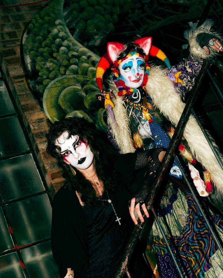 Colourful clown and goth characters with vibrant makeup at an eclectic urban setting.