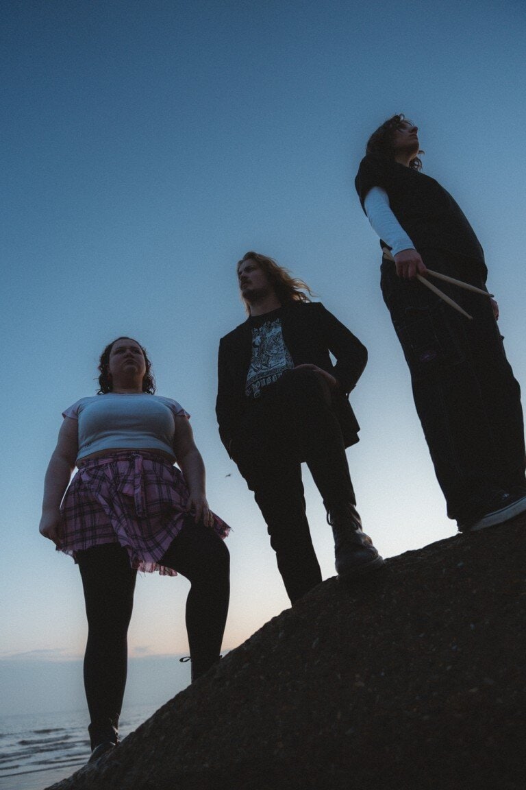 Clothing-optional group of people standing on a rocky surface against a blue sky during sunset.