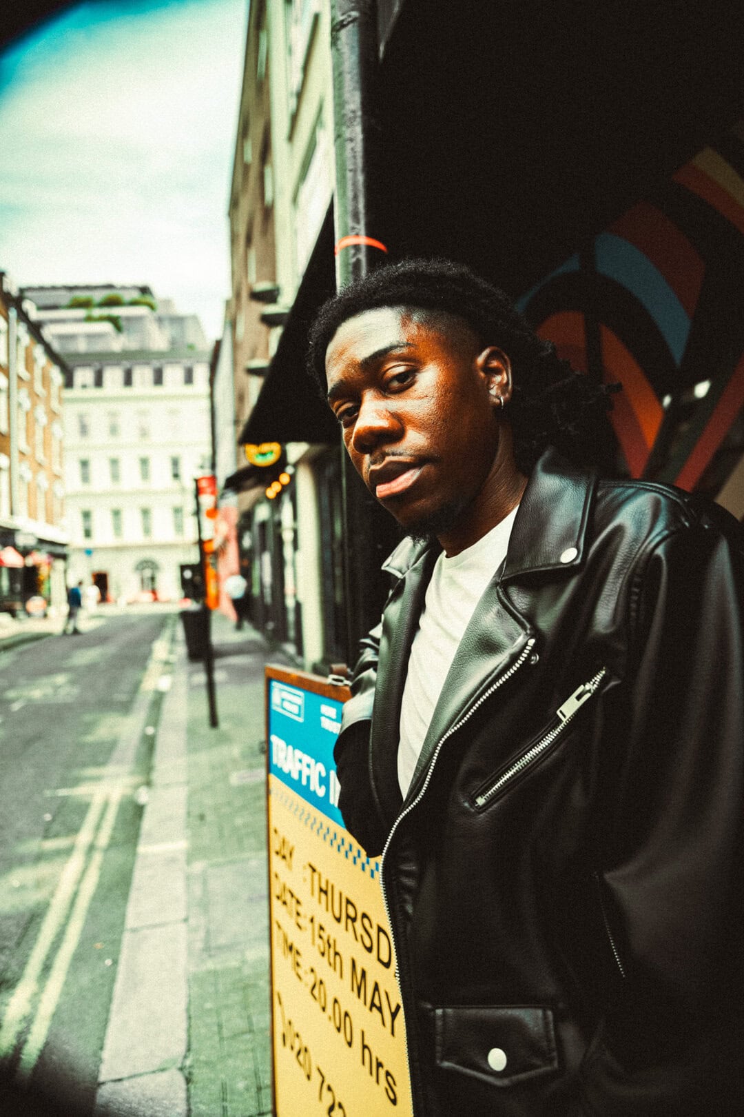 Streetscape portrait of a young man with dreadlocks in a city street, urban photography, fashionable lifestyle photography.