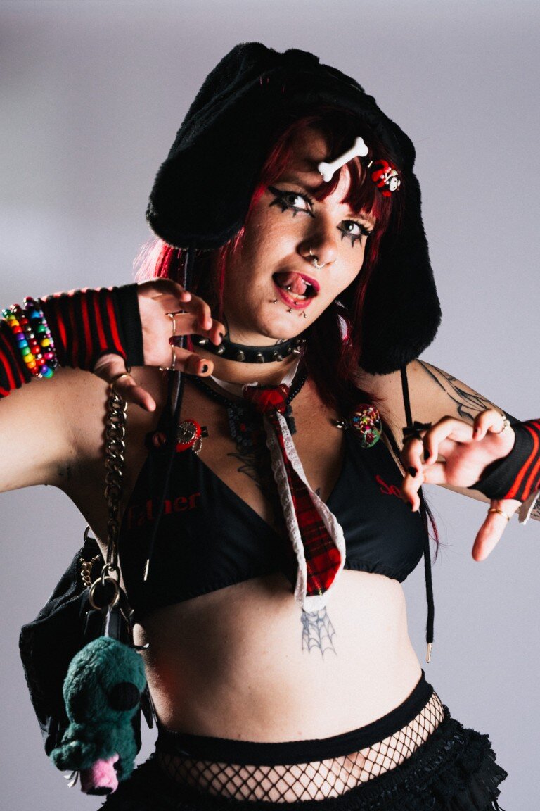 Vivid portrait of a young woman in alternative punk-inspired fashion, showcasing bold makeup, accessories, and expressive personality.