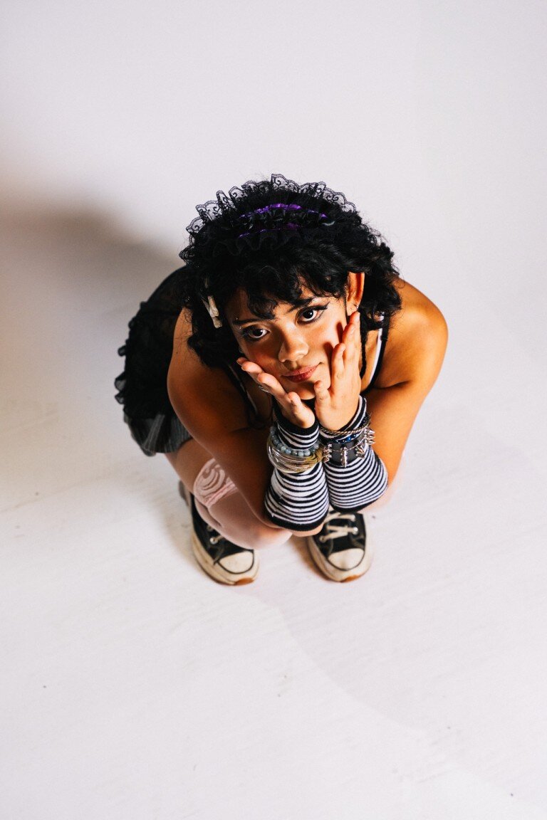 Vibrant portrait of a young woman with curly hair and eclectic style, showcasing expressive fashion photography.