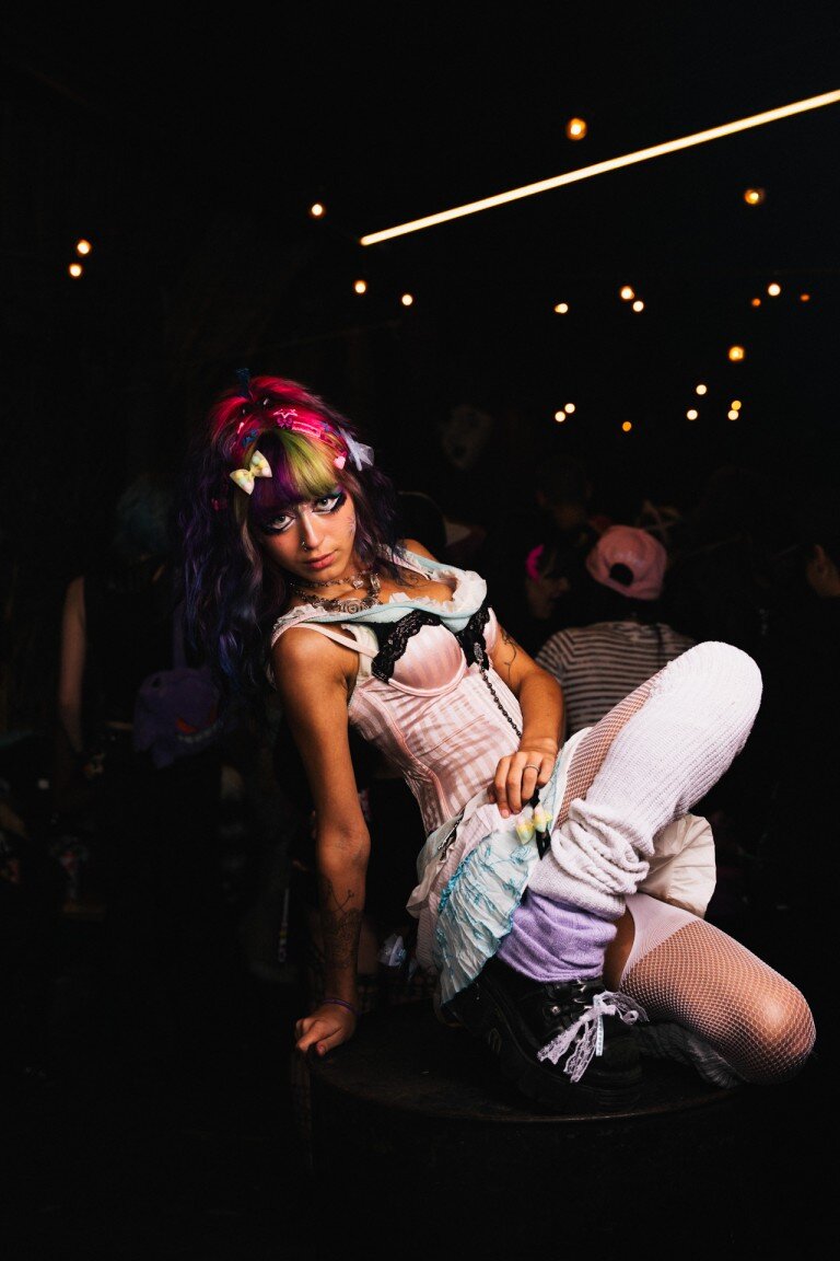 Bright colourful alternative fashion portrait with vibrant hair and unique style in a dark club setting.
