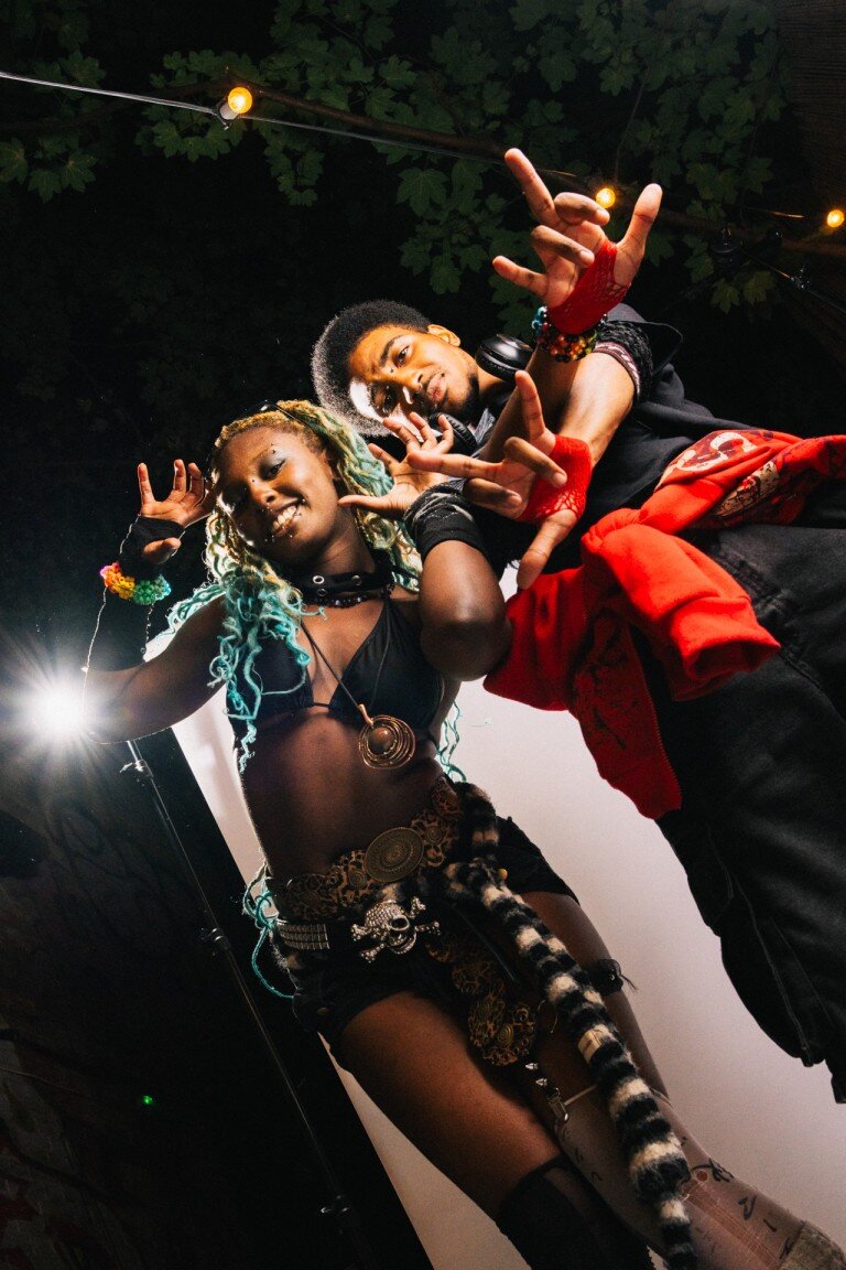 Vibrant party performers in creative costumes dancing at an indoor event.