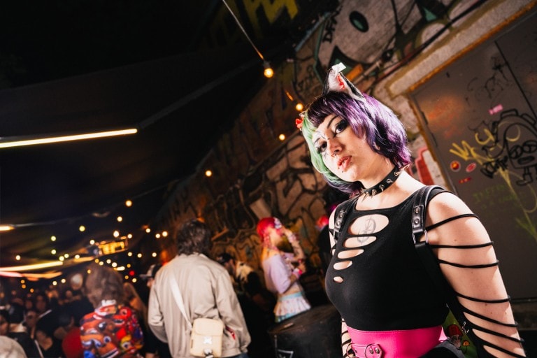 Vibrant alternative fashion portrait at night with graffiti background, showcasing edgy style and colourful hair.