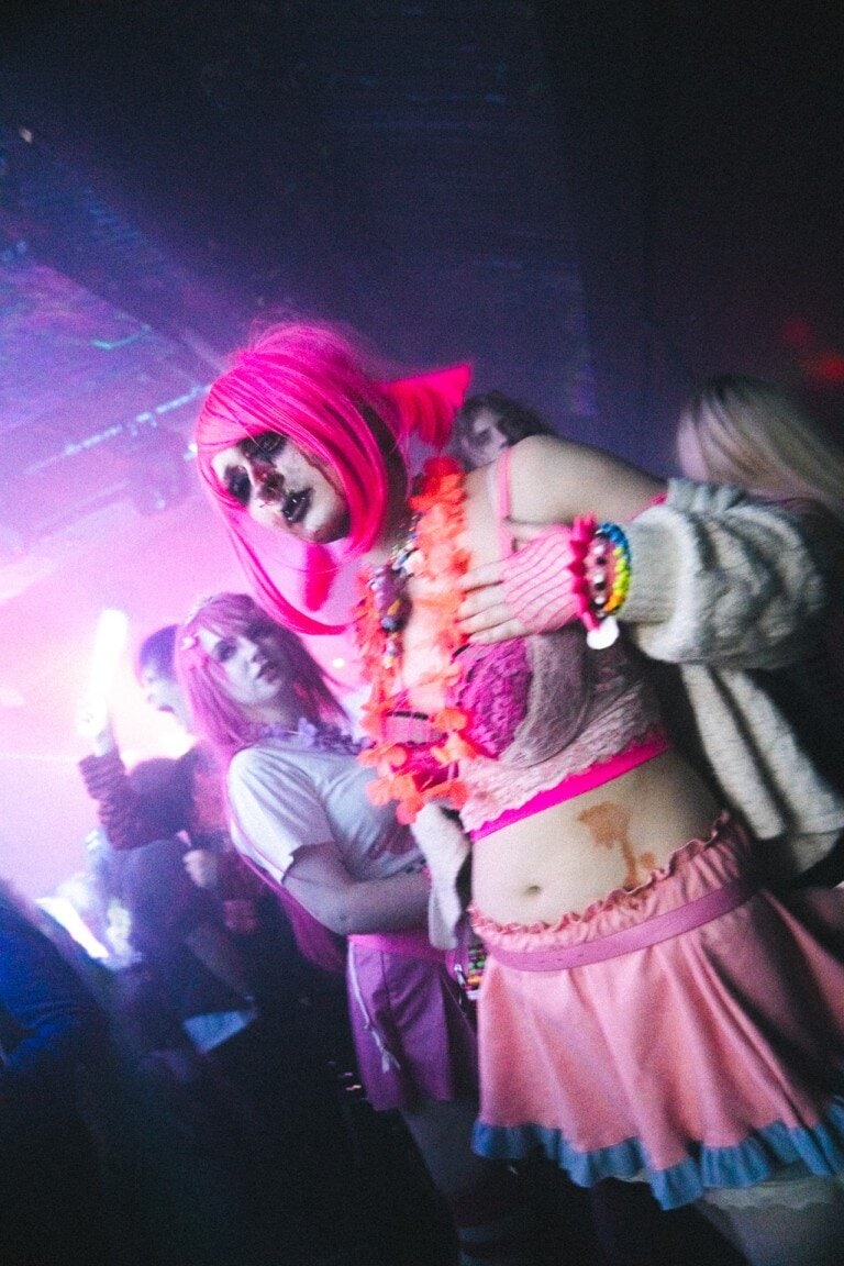 Vibrant Halloween costume party with models in colourful spooky outfits, dramatic make-up, and creative accessories at an indoor event.