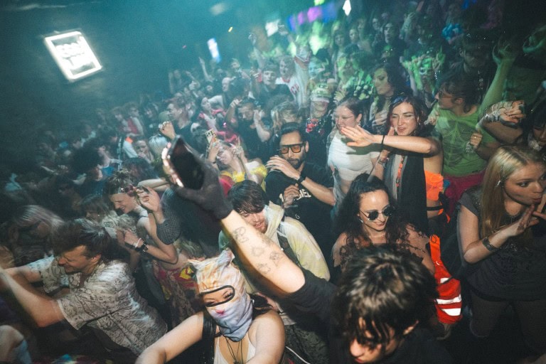 People dancing and enjoying themselves at a lively party or music event with colourful lighting and energetic atmosphere.