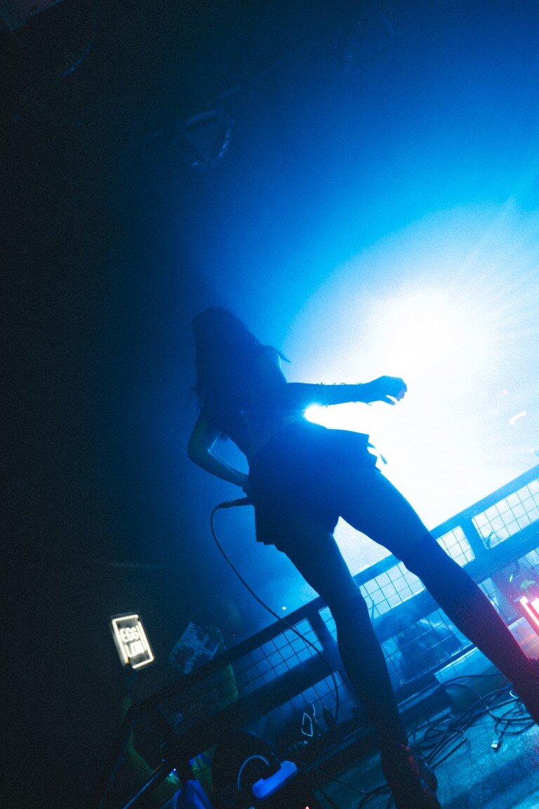 A person performing as a DJ in a nightclub with vibrant blue lighting creating a dynamic atmosphere.