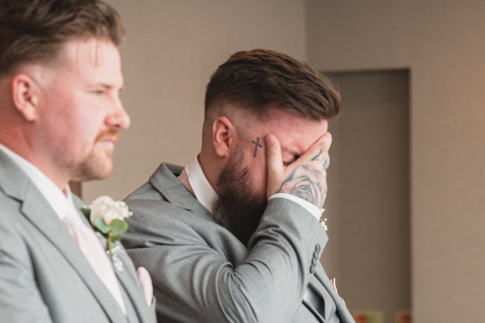 Visible, emotional moment during a formal event featuring two individuals dressed in suits, one visibly emotional and the other attentively observing.