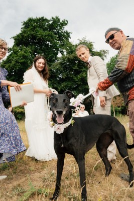 Elegant outdoor wedding ceremony with a black greyhound; professional photography capturing joyful moments in nature.