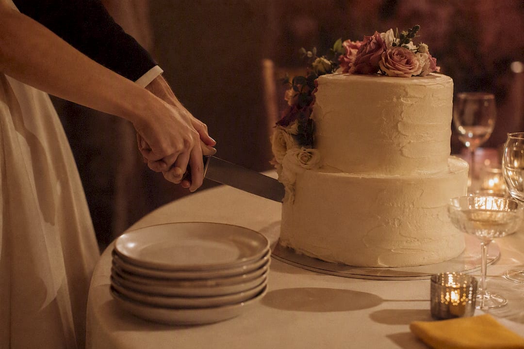 Hands cutting a wedding cake at reception