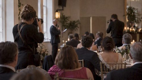 Two photographers covering wedding reception speeches